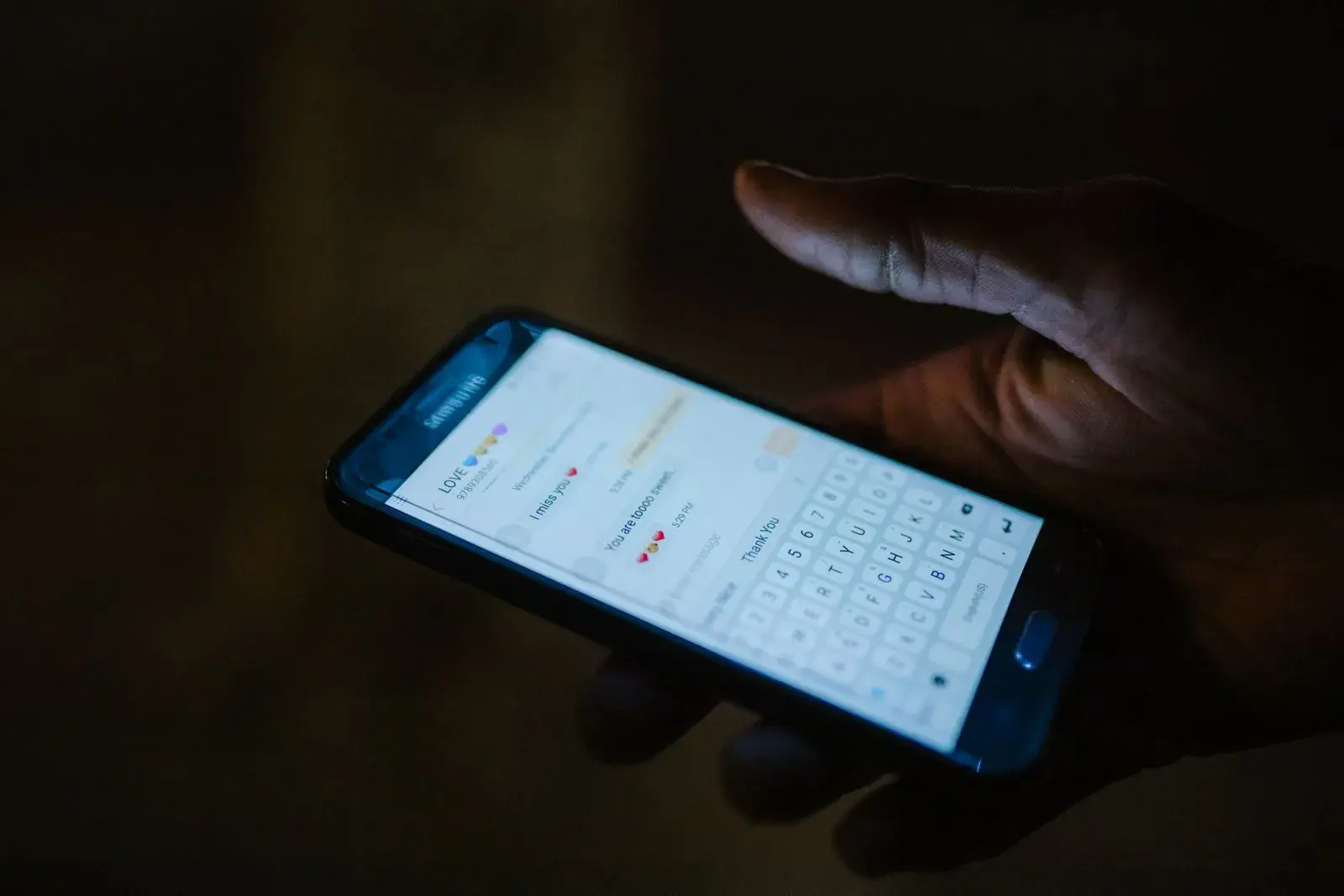 A hand holding a phone with a messaging app open