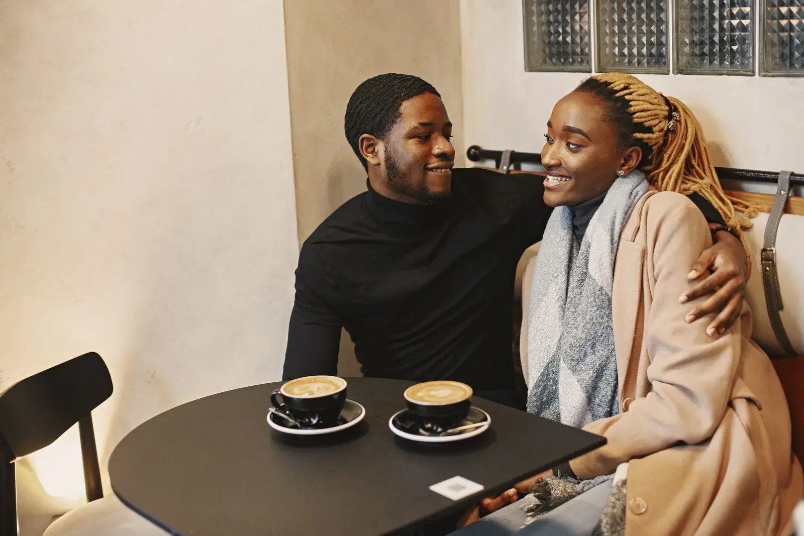 A smiling couple talking over cappuccinos in a cozy cafe