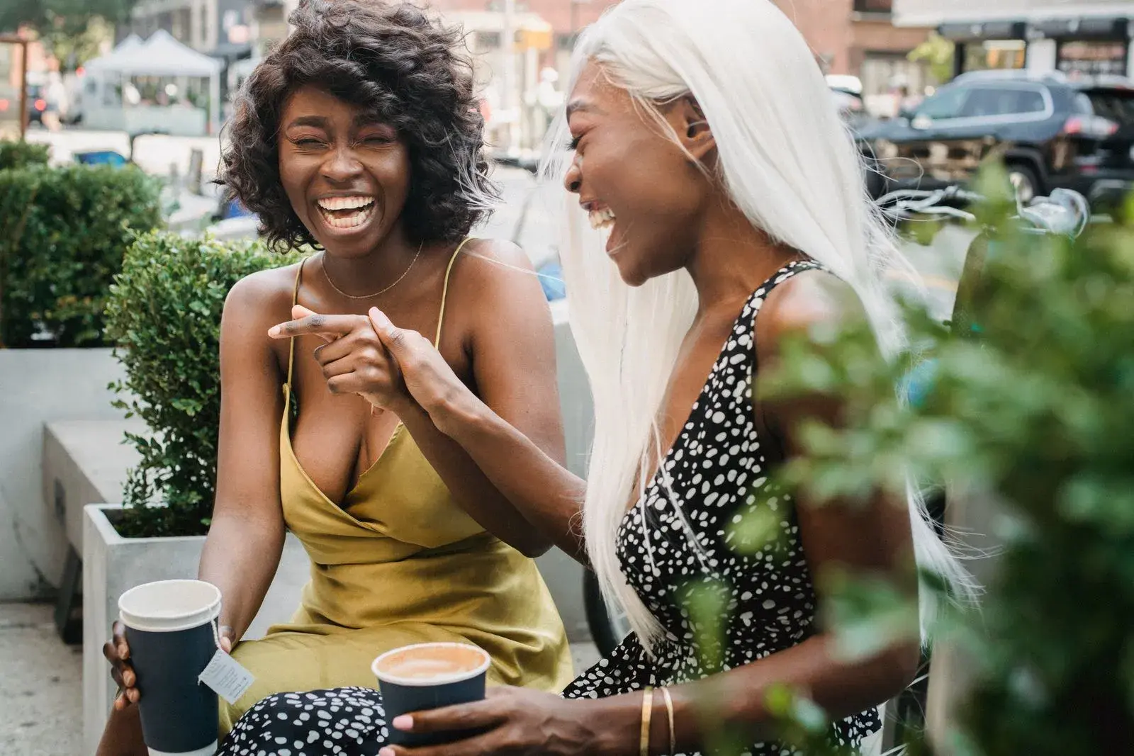 Two friends laughing together over coffee at an outdoor cafe