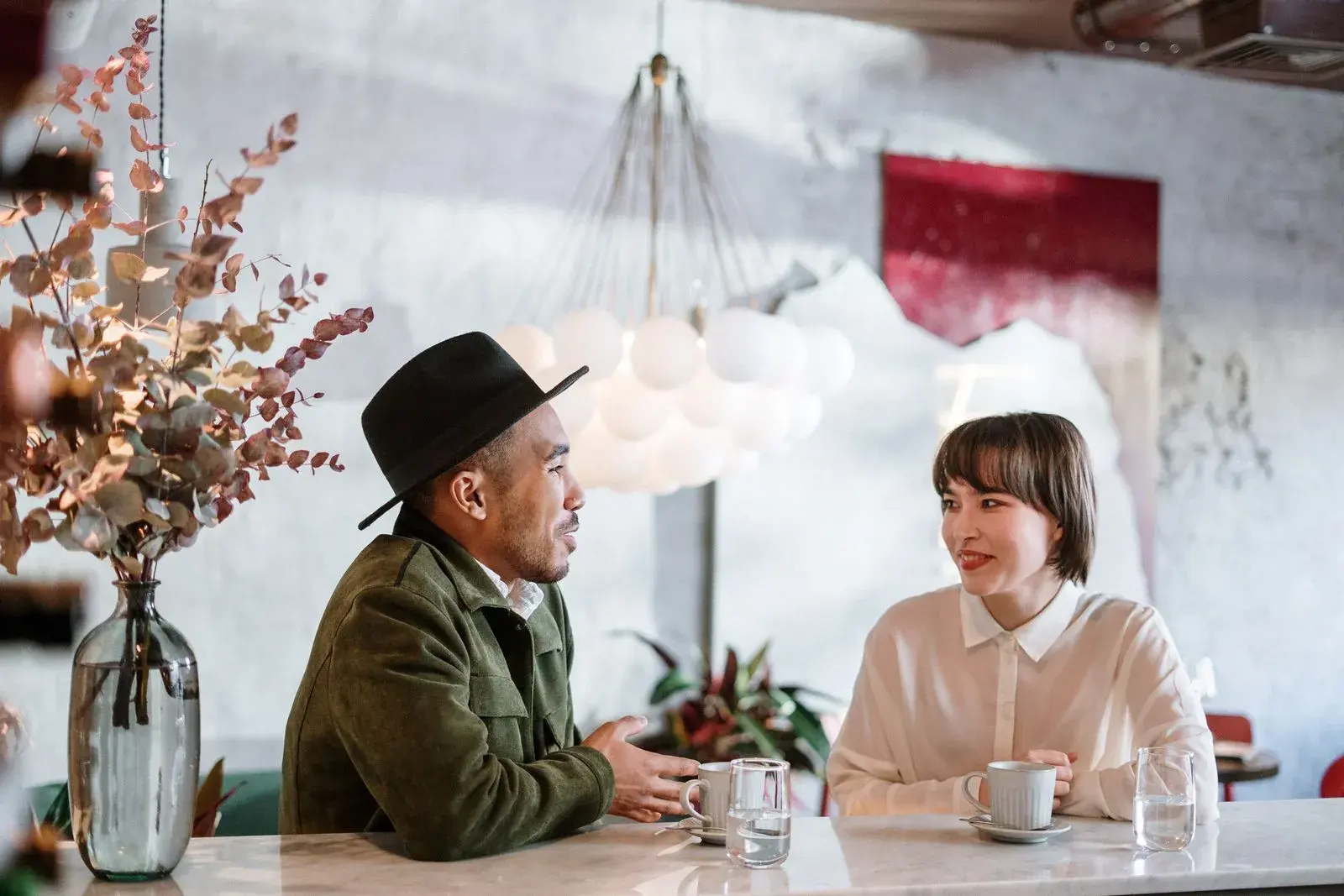 A man and a woman in easy conversation over coffee at a cafe table