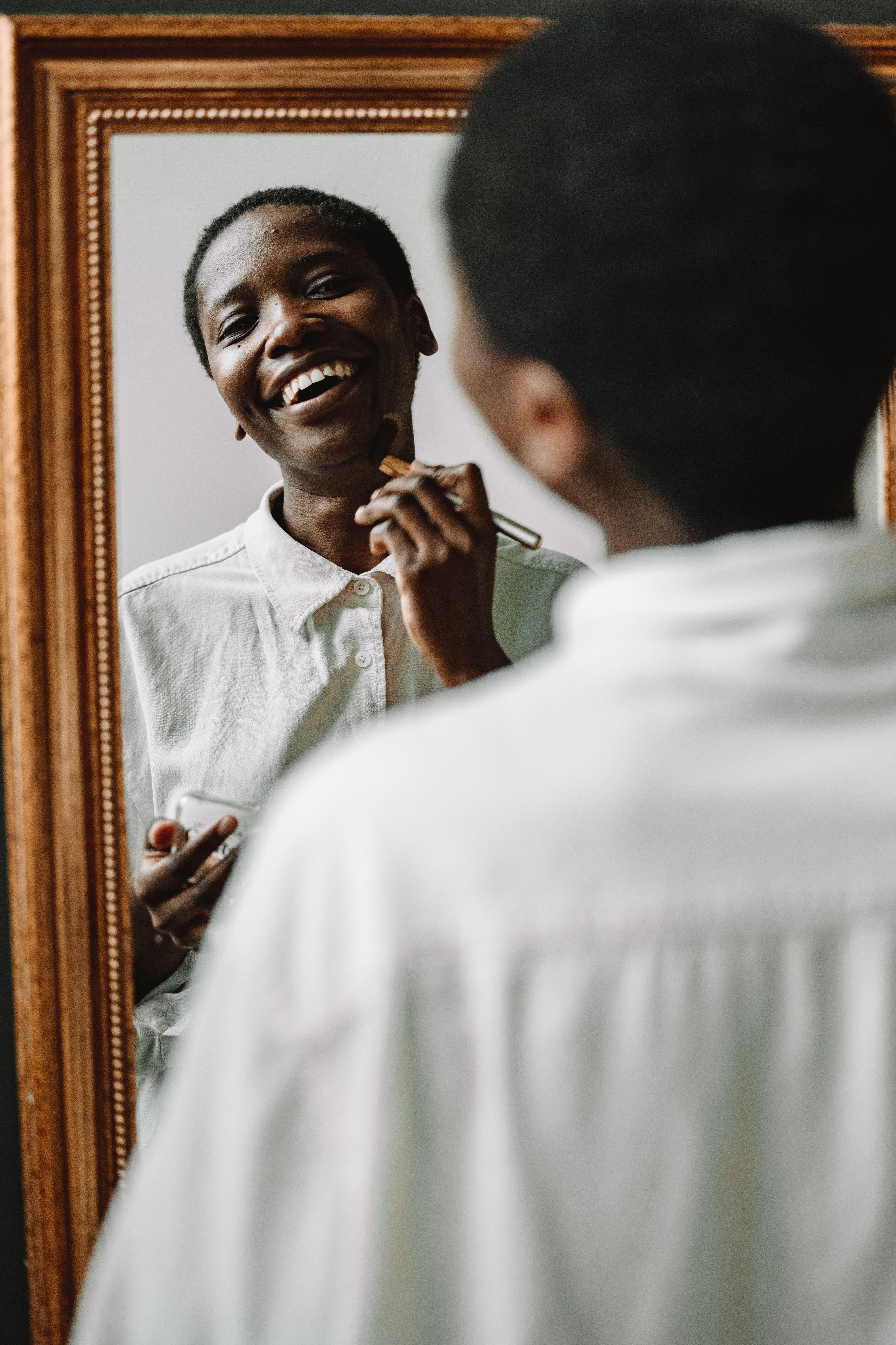 An adult smiling at their reflection while getting ready
